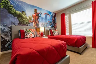 a bedroom with two red beds and a marvel mural at Prime Location 4BD Townhome with pool and Grill in Kissimmee