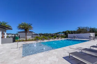 a large swimming pool with chairs at Prime Location 4BD Townhome with pool and Grill in Kissimmee