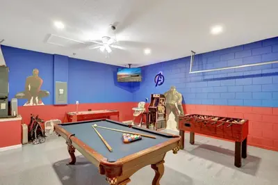 a room with a pool table and a blue wall at Luxury Pool Home 3 Miles from Disney & More! in Kissimmee