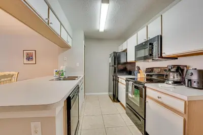 a kitchen with white counter tops and appliances at 7 Mi to Disney Condo with Pool and Hot Tub Access! in Kissimmee
