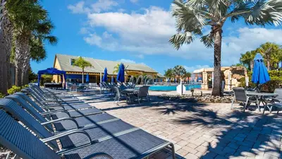 a group of chairs and umbrellas next to a pool at CPR8951 in Kissimmee