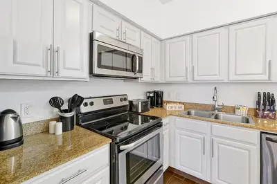 a kitchen with white cabinets and a stove top oven at 12538 INTERNATIONAL DRIVE #C303 ORLANDO 2BED in Orlando