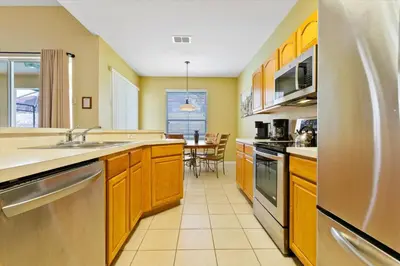 a large kitchen with wooden cabinets and a table at MNL2678 in Orlando