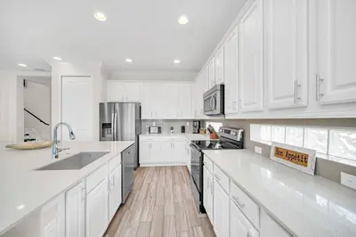 a white kitchen with white cabinets and white appliances at LAKE VILLA 6bd, all un-suite, pool, spa, grill in Kissimmee