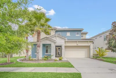 a house with a palm tree and a driveway at LAKE VILLA 6bd, all un-suite, pool, spa, grill in Kissimmee