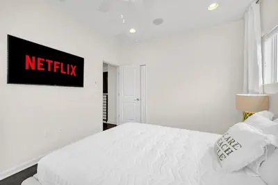 a bedroom with a white bed with a netflix sign on the wall at LAKE VILLA 6bd, all un-suite, pool, spa, grill in Kissimmee