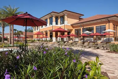 a resort with red umbrellas and tables and chairs at Luxury Townhome Near Disney w/ Resort Amenities in Orlando