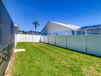 a fence with a grass yard next to a building at Relax Away Villa: Private Pool Home Near Disney in Orlando