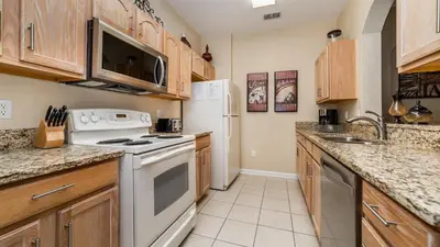 a kitchen with white appliances and wooden cabinets at ALM2809-101 in Orlando