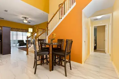 a dining room with orange walls and a table and chairs at DVL2638 in Orlando