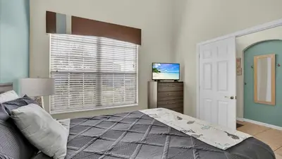 a bedroom with a bed and a television and a window at FP8176 Windsor Palms Resort Vacation Home in Kissimmee