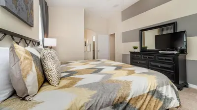 a bedroom with a bed with a dresser and a television at FP8190 Windsor Palms Resort Vacation Home in Kissimmee