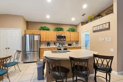 a kitchen with a counter and chairs and a refrigerator at FP8104 Windsor Palms Resort Vacation Home in Kissimmee