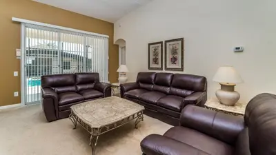 a living room with leather furniture and a large window at FP8147 Windsor Palms Resort Vacation Home in Kissimmee