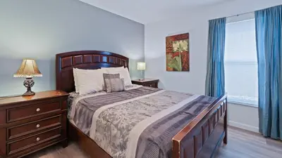 a bedroom with a bed and a dresser with a lamp at FP8159 Windsor Palms Resort Vacation Home in Kissimmee