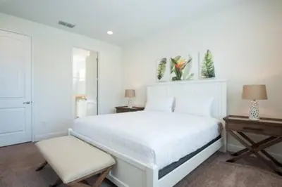 a white bedroom with a white bed and a chair at Contemporary Disney VacationHome in Orlando