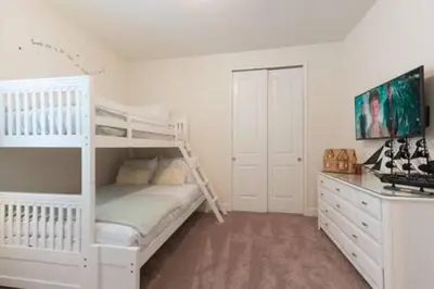 a bedroom with a white bunk bed and a dresser at Contemporary Disney VacationHome in Orlando