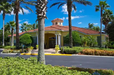 a yellow building with palm trees in front of it at Spacious Emerald Escape - 12 Mins to Disney in Kissimmee