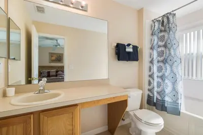 a bathroom with a sink and a toilet and a mirror at Spacious Regal Oaks Retreat - Steps to the Pool in Orlando