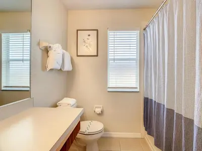 a bathroom with a toilet and a sink and windows at Spacious Regal Oaks Townhome by Disney in Orlando