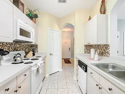 a kitchen with white cabinets and a sink at Spacious Windsor Palms Retreat - 11 Min to Disney in Kissimmee