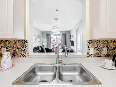 a kitchen with a sink and a living room at Spacious Windsor Palms Retreat - 11 Min to Disney in Kissimmee