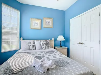 a bedroom with blue walls and a bed with a white bedspread at Spacious Windsor Palms Retreat - 11 Min to Disney in Kissimmee