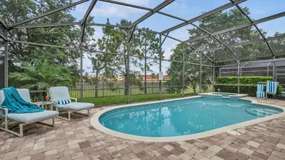 a swimming pool with two chairs and a pergola at CW7739 Windsor Hills Resort Vacation Home in Orlando