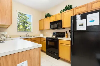 a kitchen with a black refrigerator and wooden cabinets at Stunning Regal Oaks 4BR w/ Pool, Spa & Near Disney in Orlando