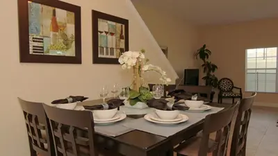 a dining room table with chairs and a black table with flowers at CAL8967 in Kissimmee