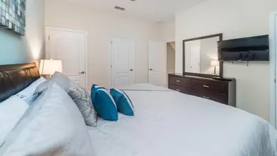 a bedroom with a large white bed with blue pillows at CAP8875 in Kissimmee