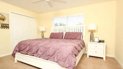 a bedroom with a bed with a purple comforter and a window at CAP8883 in Kissimmee