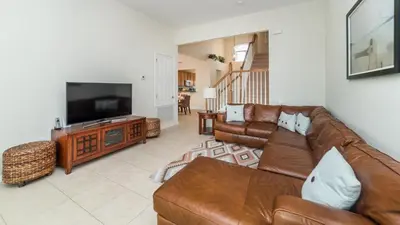 a living room with a couch and a flat screen tv at Amazing 5 BR Home with Pool Windsor Hills Resorts in Orlando