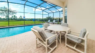 a patio with a table and chairs and a pool at Amazing 5 BR Home with Pool Windsor Hills Resorts in Orlando