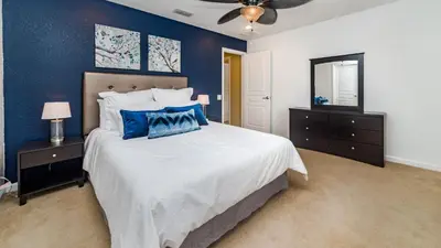 a bedroom with a large bed with blue walls at Huge 6BR Home in Windsor Hills Resort in Orlando