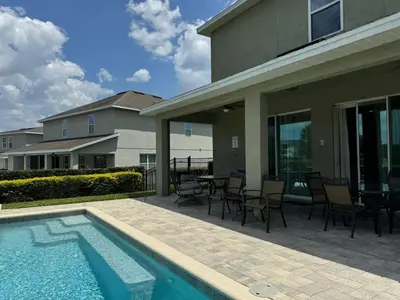 a patio with a table and chairs next to a swimming pool at Luxury 6BD Encore Resort Disney Pvt Pool Game Room Near Disney Water Park in Orlando