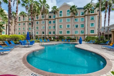 a pool in front of a hotel with palm trees at Disney Accessibility Star Wars Vacation Apartment Near Parks in Orlando