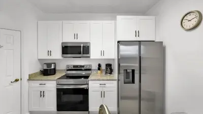 a kitchen with white cabinets and a stainless steel refrigerator at BF 2Bedrooms 2303 - 102 in Kissimmee