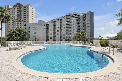a large swimming pool in front of a building at 6165 CARRIER DR #1212 ORLANDO 1BED in Orlando