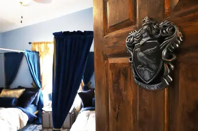 a wooden door with a crest on it next to a bed at Magical 5-Bedroom Villa Near Universal's Wizarding World in Kissimmee
