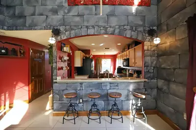 a kitchen with a stone wall with stools at a bar at Enchanted Villa with Lake View 6-Bedroom in Resort 9 miles to Disney World 15 miles to the Wizarding World of Harry Potter in Kissimmee