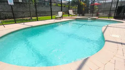 a large blue swimming pool with two chairs in it at 6-Bedroom 2505 in Orlando