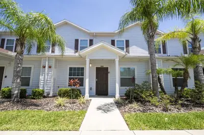 a white house with palm trees in front of it at Villa Coelho - West Lucaya Resort in Kissimmee