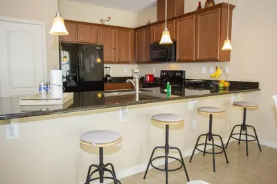 a kitchen with wooden cabinets and bar stools at Villa Compass- Compass Bay in Kissimmee