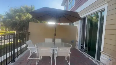 a table with chairs and an umbrella on a patio at Magic Villa Orlando in Orlando