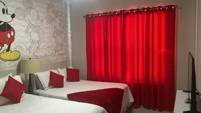 a bedroom with red curtains and two beds with white sheets at Disney here we go in Orlando