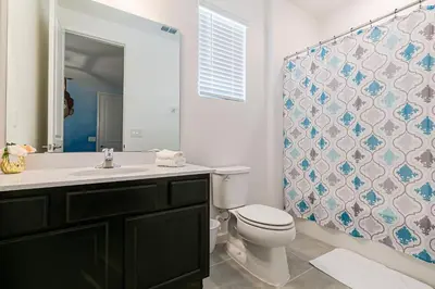a bathroom with a toilet and a sink and a mirror at 2476 SHANTI DRIVE 12BED in Kissimmee