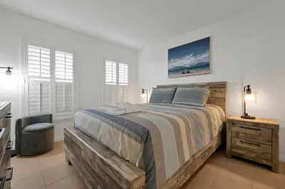 a white bedroom with a large bed and a chair at 2728 CLUB CORTILE CIRCLE UNIT A 3BED in Kissimmee