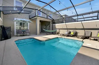 a swimming pool with a hammock and chairs in a house at Top Rated 4BR home in Kissimmee