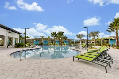 a swimming pool with green benches and palm trees at Top Rated 4BR home in Kissimmee